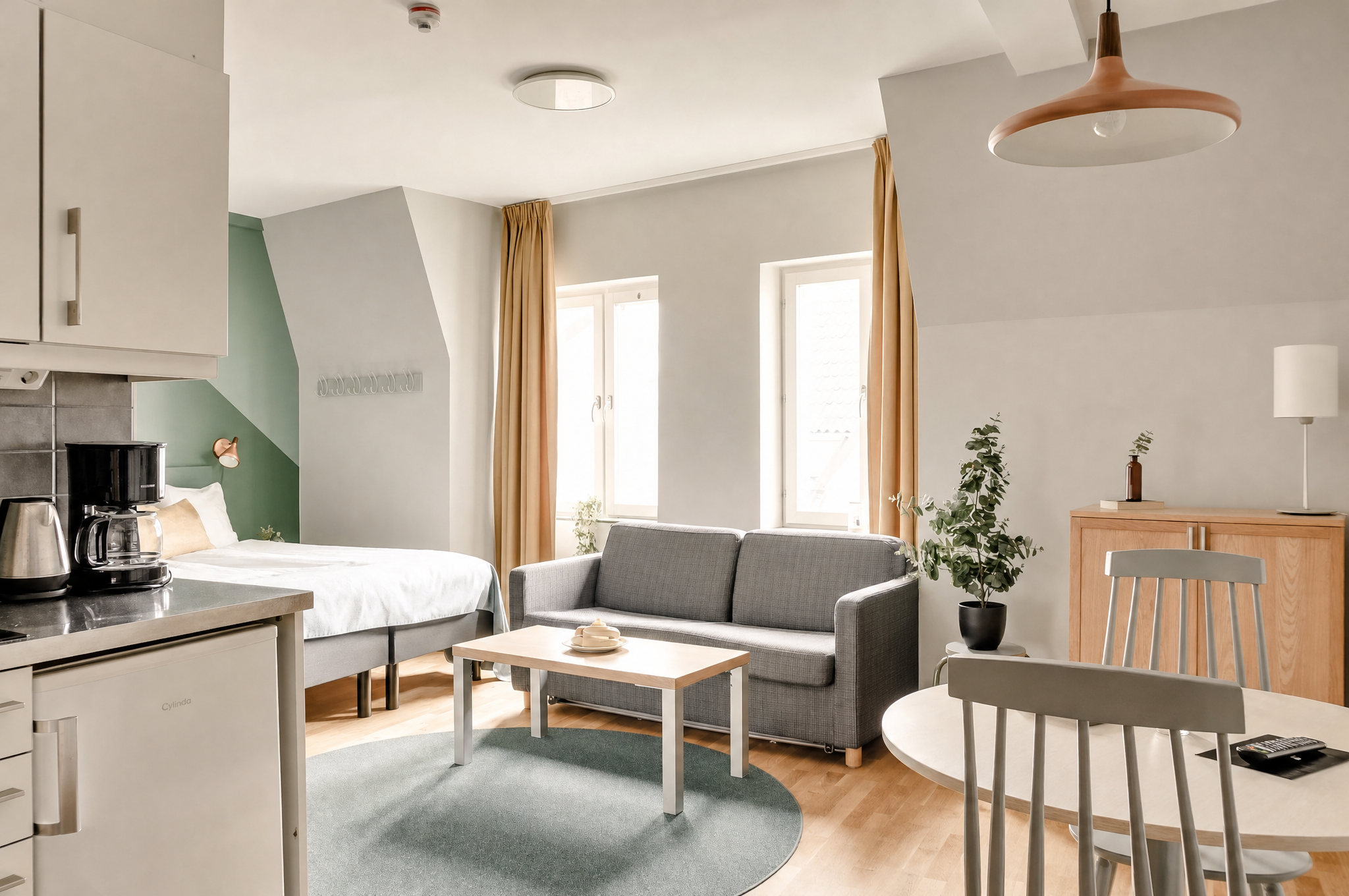 Open-plan living area with sofa, dining table and compact kitchen